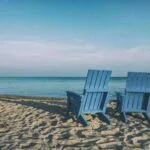 2 deckchairs on a beach facing out to sea to represent retirement