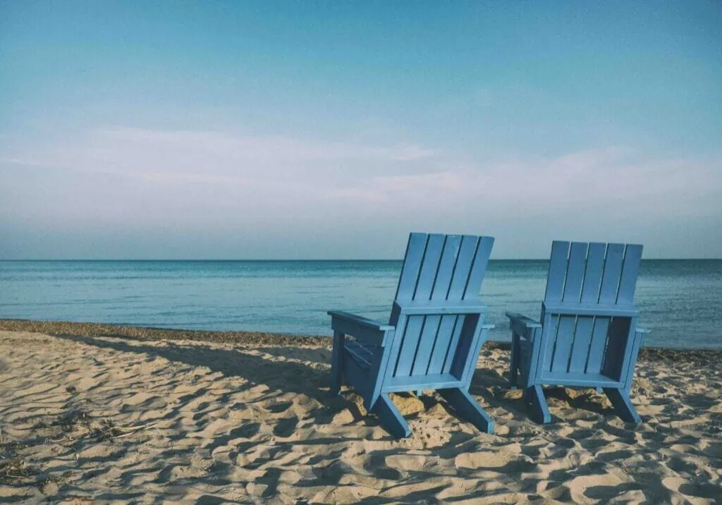 2 deckchairs on a beach facing out to sea to represent retirement